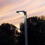 A shielded LED outdoor streetlight against a setting sky.