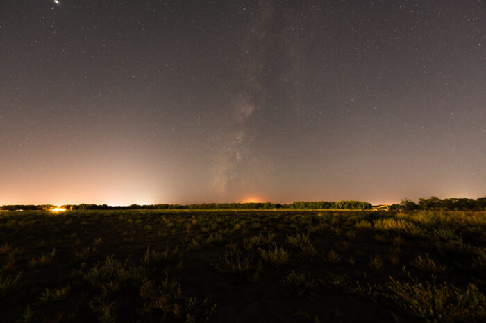View of the Milky Way peering over distant light domes at Valle de Oro National Wildlife Refuge. Photo credit: Andy Jones